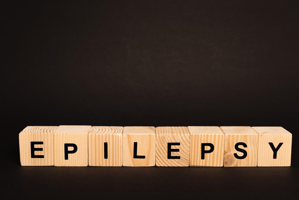 Houten blokjes met epilepsie letters geïsoleerd op zwart - Foto, afbeelding