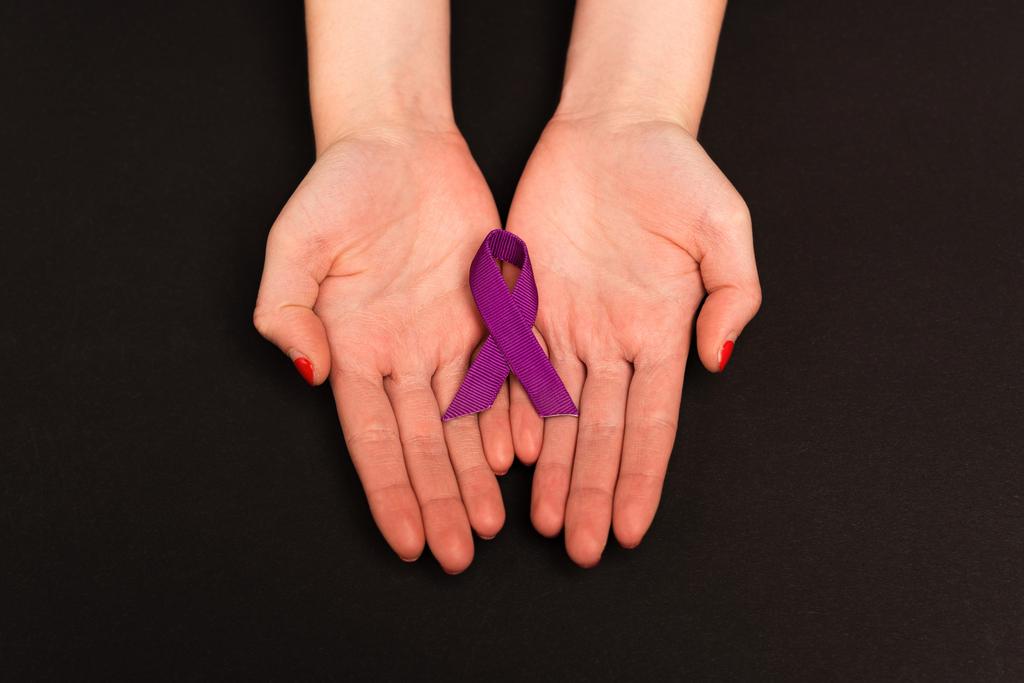 Widok góry fioletowej wstążki na rękach kobiety odizolowanej na czarno - Zdjęcie, obraz