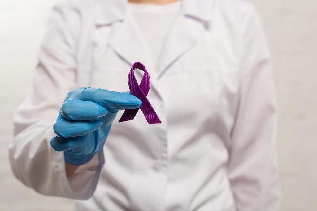 Enfoque selectivo del médico sosteniendo cinta púrpura sobre fondo blanco
 - Foto, Imagen