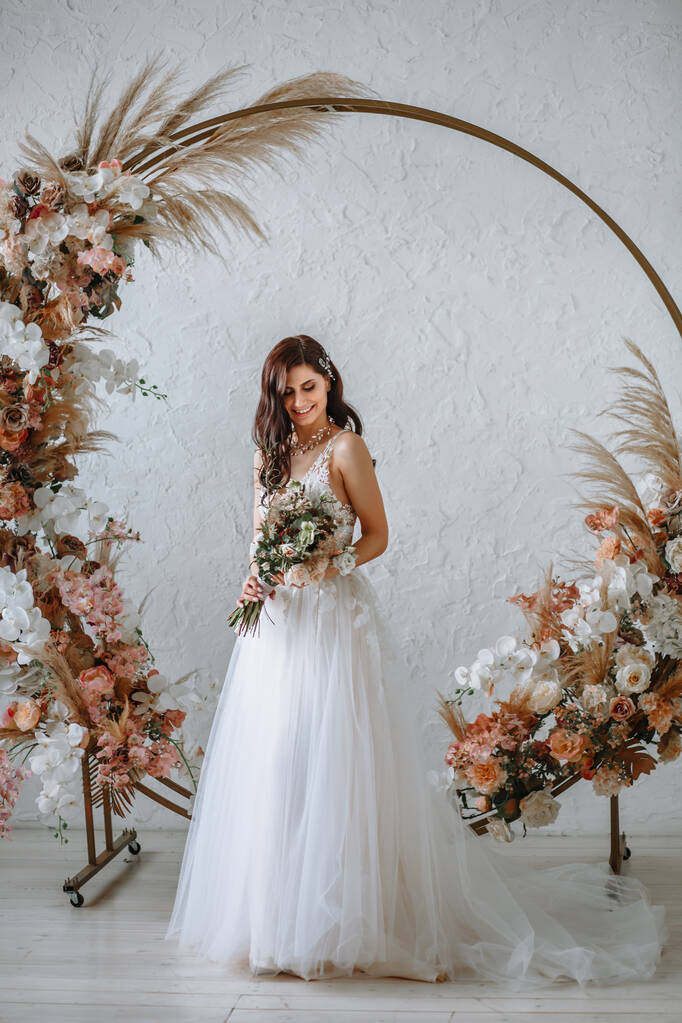 Šťastná nevěsta ve svatebních šatech s kyticí v rukou - Fotografie, Obrázek