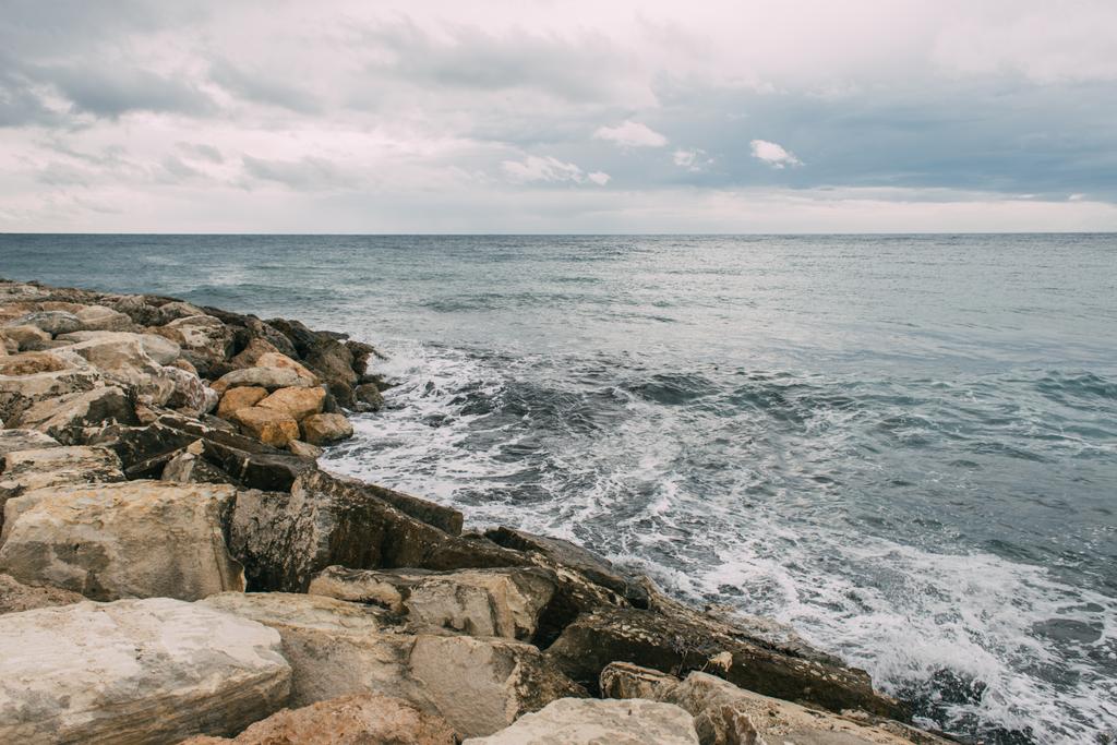 tranquil coastline with rocks near mediterranean sea against cloudy sky  - Photo, Image