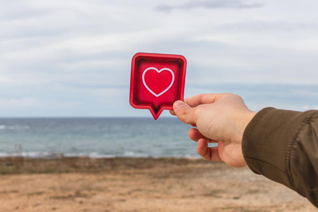 άνθρωπος κρατώντας χάρτινη καρδιά κοντά στη Μεσόγειο θάλασσα - Φωτογραφία, εικόνα