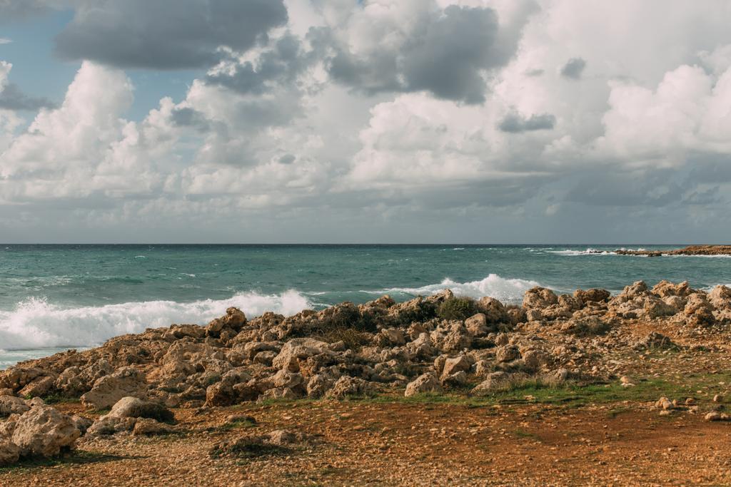 ηλιοφάνεια σε βράχια κοντά στη Μεσόγειο θάλασσα ενάντια στον ουρανό με λευκά σύννεφα  - Φωτογραφία, εικόνα