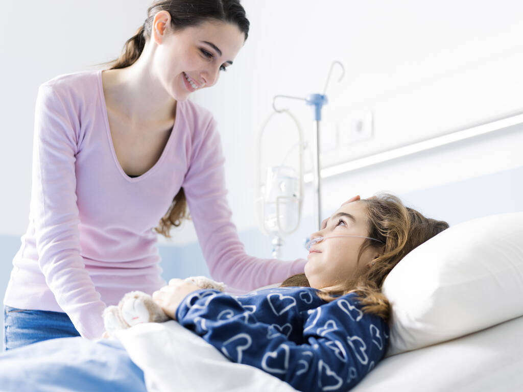 Giovane donna che assiste il suo bambino malato sdraiato a letto in ospedale, pediatria e concetto di assistenza sanitaria
 - Foto, immagini