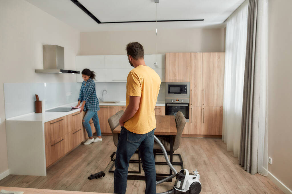 Casa limpa, vida saudável. Jovens e felizes casal multicultural em roupas casuais limpeza de sua cozinha moderna juntos
 - Foto, Imagem