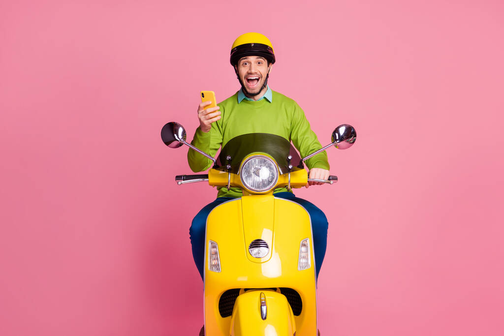 Retrato dele ele agradável atraente positivo alegre alegre cara andando de moto usando a internet de navegação celular como reação isolada sobre cor pastel rosa fundo
 - Foto, Imagem