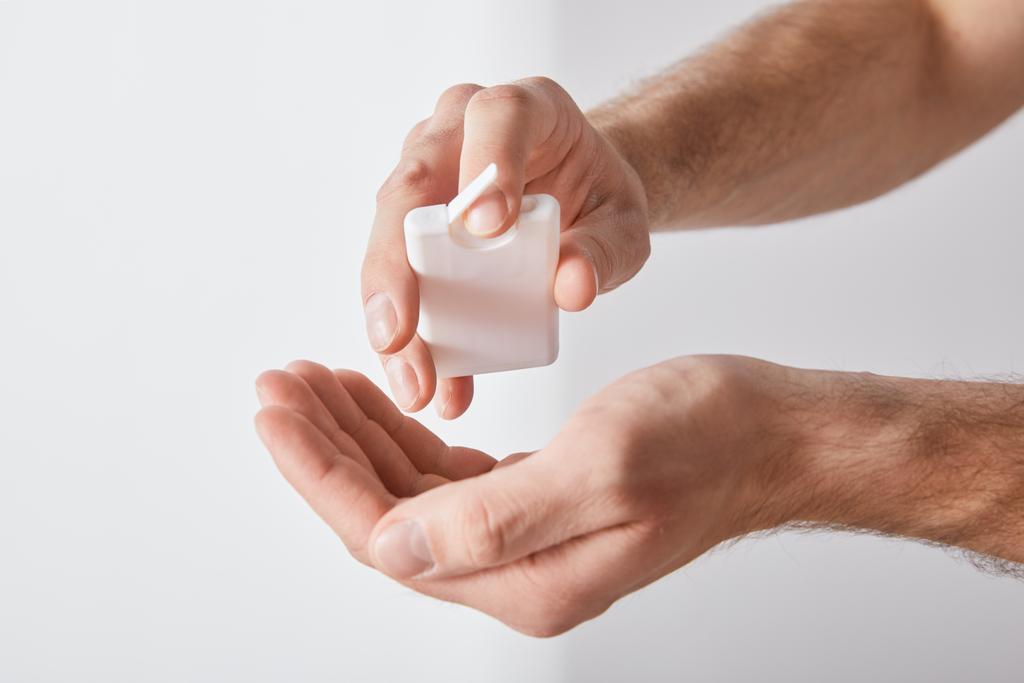 cropped view of adult man using hand sanitizer on white background - Photo, Image