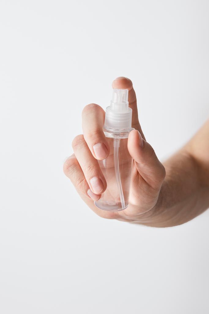 vista recortada del hombre que sostiene el desinfectante de la mano en botella del aerosol aislada en blanco
 - Foto, Imagen