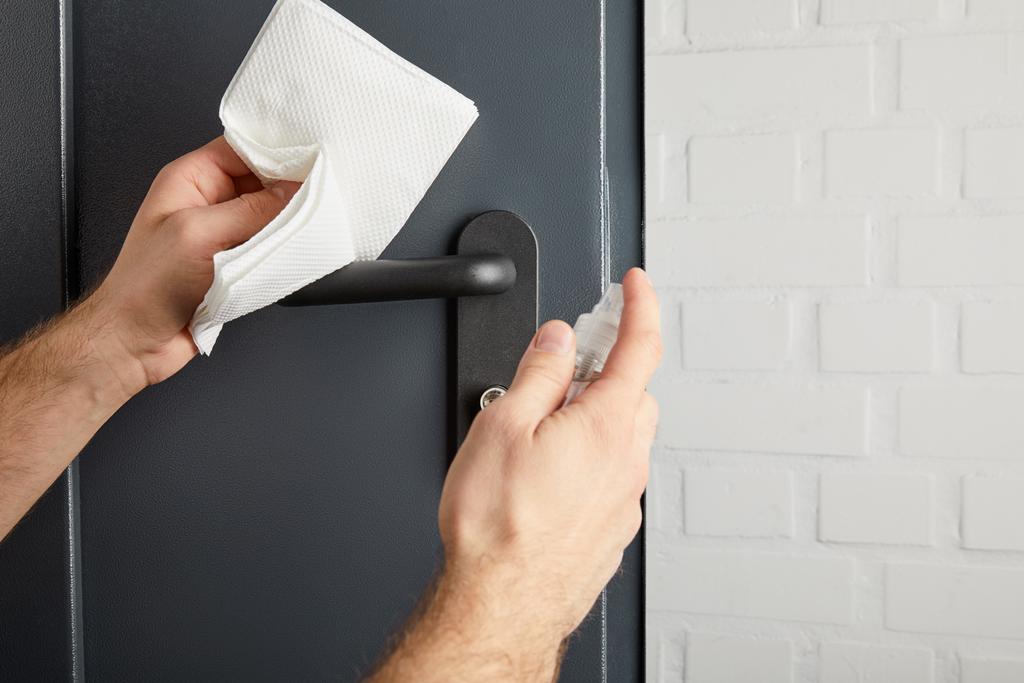 partial view of man disinfecting metal door handle with antiseptic and napkin - Photo, Image