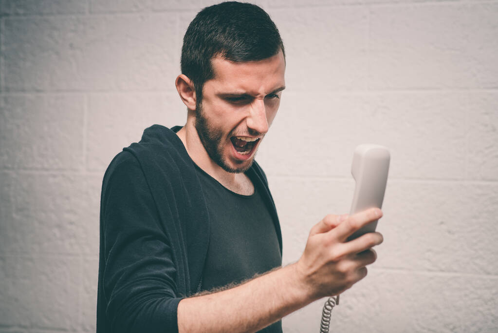 Κοντινή εικόνα ενός άνδρα να ουρλιάζει στο τηλέφωνο κατά τη διάρκεια της συζήτησης. - Φωτογραφία, εικόνα