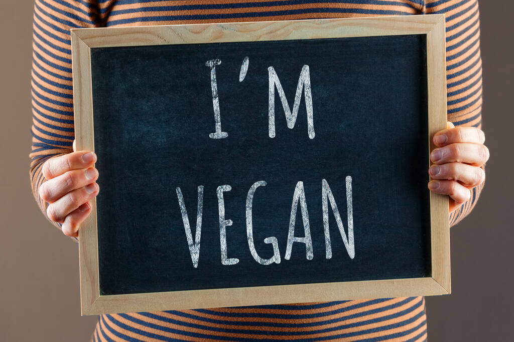 Weibliche Hände halten kleine schwarze Tafeln vor den Körper mit der Aufschrift "Ich bin Veganerin" - Foto, Bild