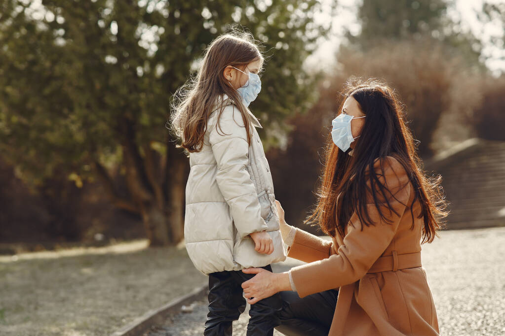 Moeder met dochter loopt buiten in maskers - Foto, afbeelding