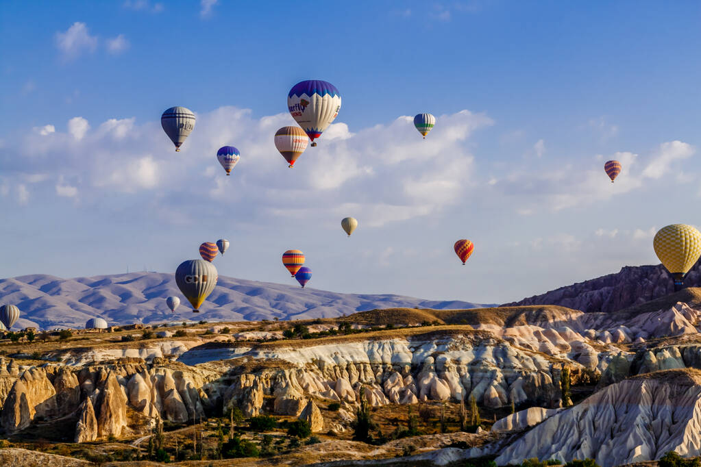 Goreme / Nevsehir, Törökország - 2019. szeptember 27.: Színes hőlégballonok repülnek a völgy felett Cappadociában, Anatóliában, Törökországban. Vulkanikus hegyek a Goreme Nemzeti Parkban. - Fotó, kép