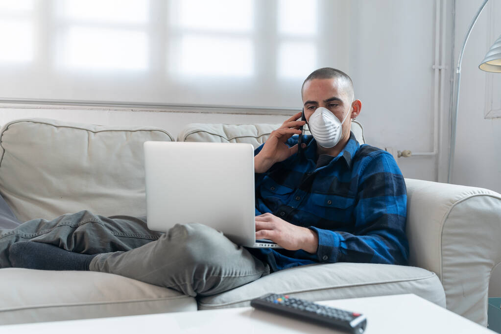 Coronavirus. Man at home wearing protective mask. Woman in quarantine for coronavirus on the couch cleaning her hands with sanitizer gel. Working from home. Clean your hands with sanitizer gel.  - Photo, Image