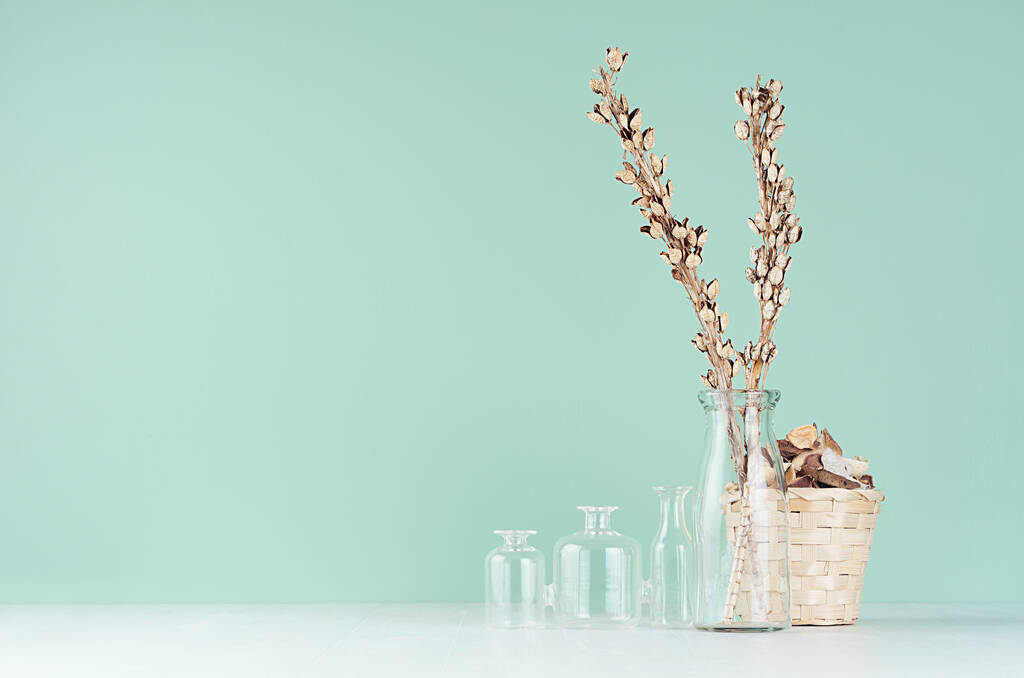 Σύγχρονο εσωτερικό σε μοντέρνο mint menthe χρώμα με μπεζ ξηρό φυτό, λουλούδια, ψάθινο καλάθι και γυάλινα βάζα σε μαλακό ανοιχτό λευκό ξύλινο τραπέζι. - Φωτογραφία, εικόνα
