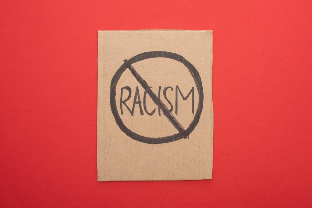 vista superior del cartel de cartón con el signo de racismo de parada sobre fondo rojo
 - Foto, Imagen