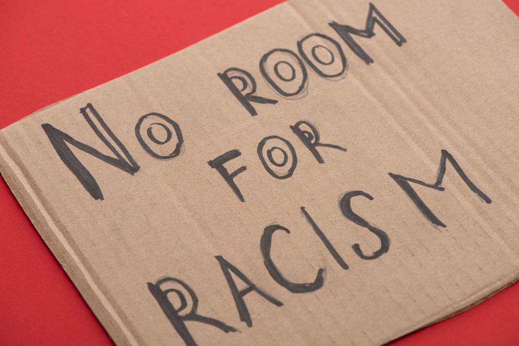 картонный плакат с надписью "нет места для расизма" на красном фоне
 - Фото, изображение