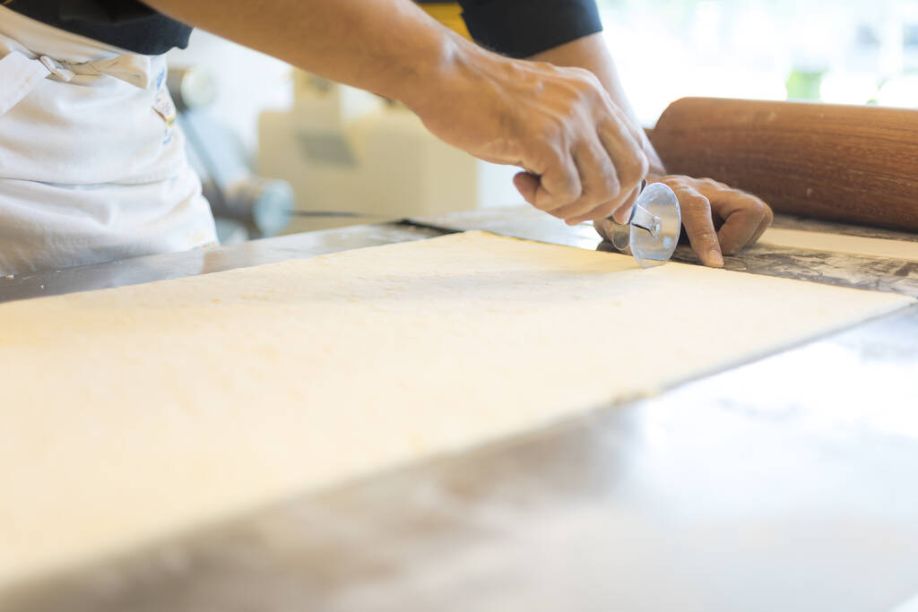 férfi a konyhában vágás tészta croissant  - Fotó, kép
