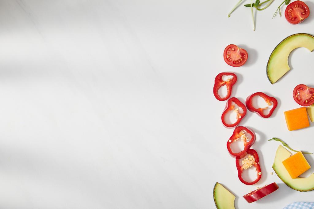 Top näkymä leikattu chili, kurpitsa ja kirsikkatomaatit avokado viipaleita valkoisella pohjalla
 - Valokuva, kuva