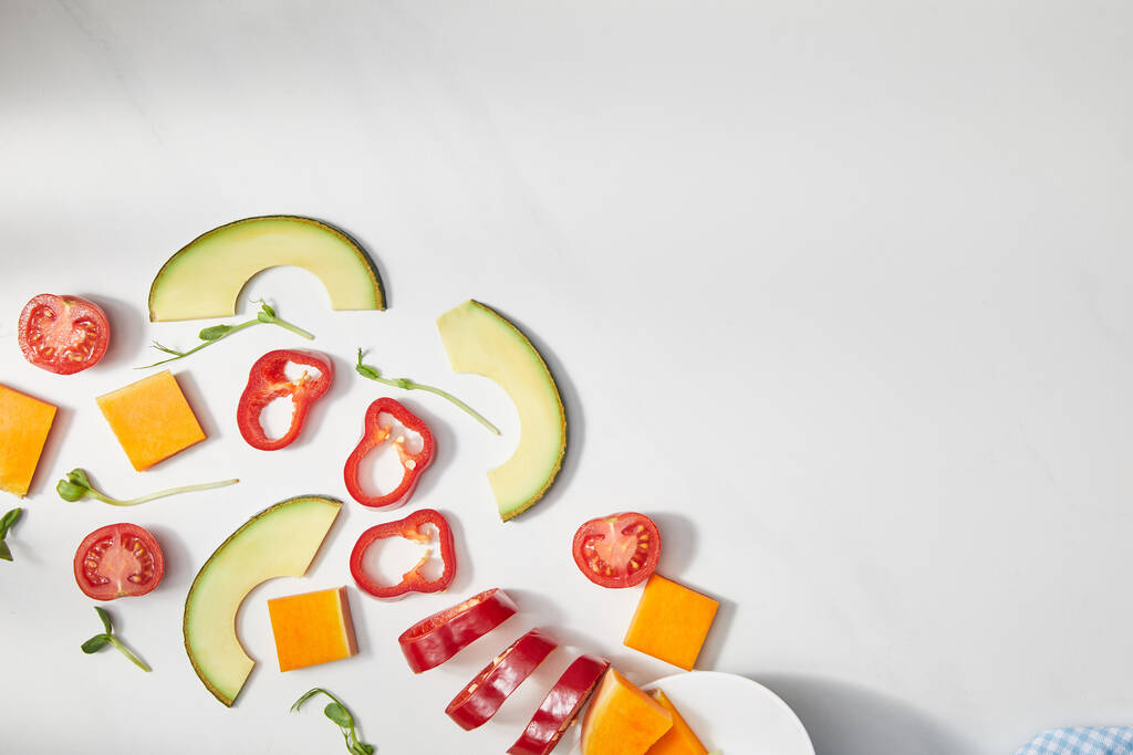 Vista superior de microgreens, chile cortado, calabaza y tomates cherry con rodajas de aguacate sobre fondo blanco
 - Foto, Imagen