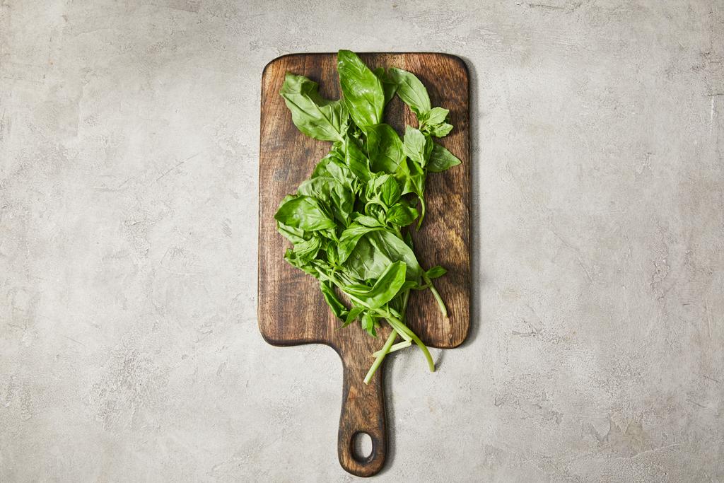 Top view of cutting board with basil leaves on grey background - Photo, Image