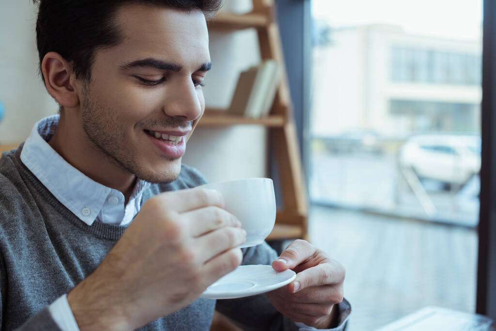 Επιχειρηματίας χαμογελά και κρατώντας πιατάκι με φλιτζάνι καφέ  - Φωτογραφία, εικόνα