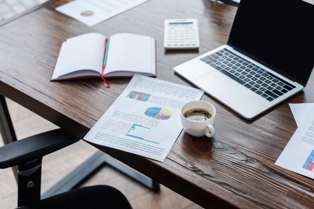 Вибірковий фокус чашки кави біля паперу, ноутбука та ноутбука на столі в офісі
 - Фото, зображення