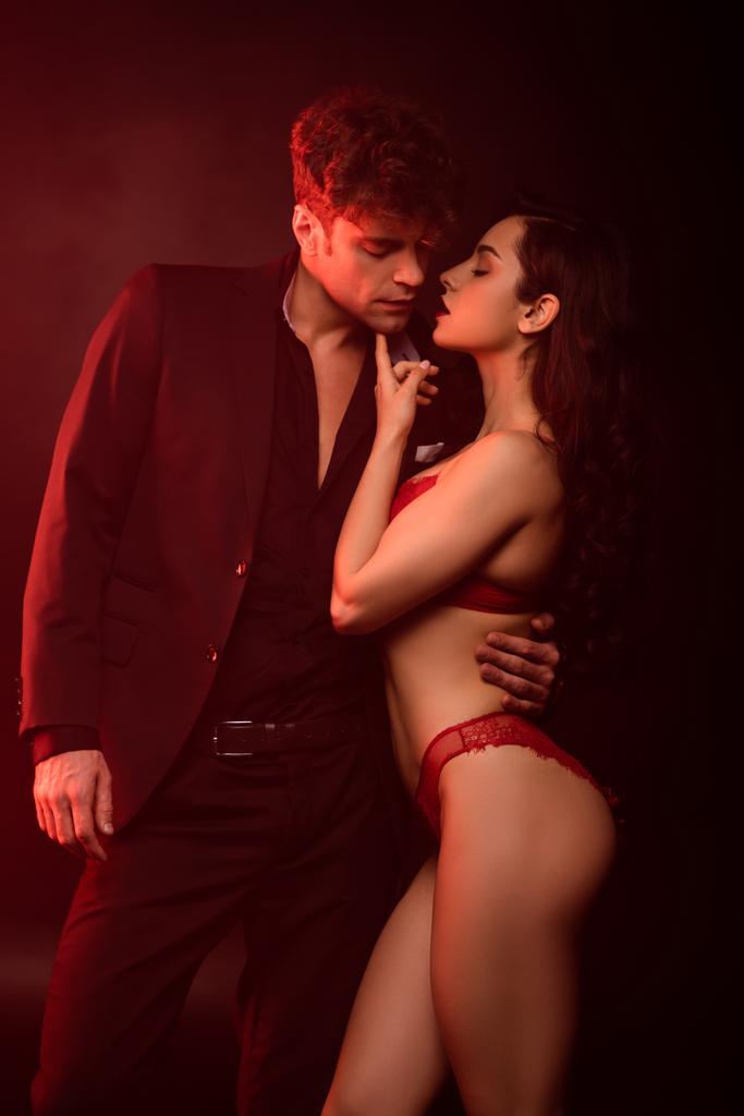 couple intime étreignant et allant embrasser sur noir avec la lumière rouge
 - Photo, image