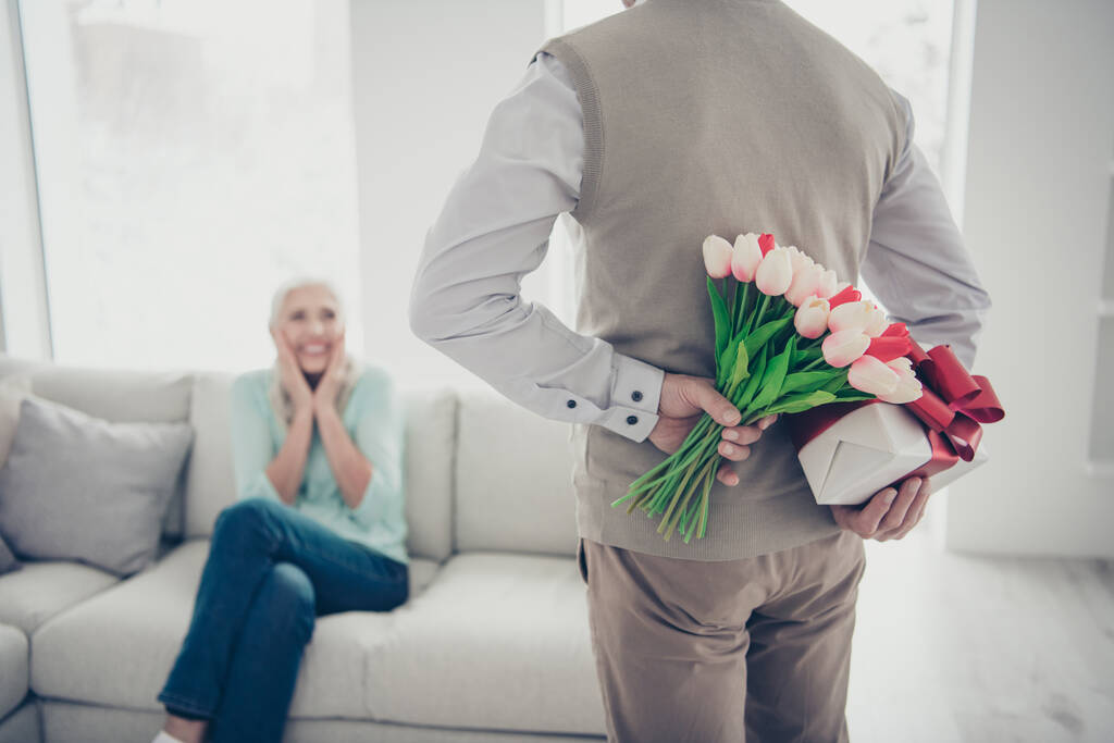 Romantyczna randka dla dwóch osób w podeszłym wieku mężczyzna trzymać tulipany pęczek i pudełko prezentów za plecami niespodziewana niespodzianka - Zdjęcie, obraz
