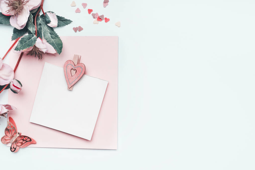 Ευχετήρια κάρτα mock up με παστέλ ροζ καρδιά και λουλούδια σε λευκό φόντο, πάνω άποψη, σύνορα. Επίπεδη. Μπορεί να χρησιμοποιήσει για την Ημέρα της Μητέρας, γάμος, γενέθλια, Ημέρα του Αγίου Βαλεντίνου - Φωτογραφία, εικόνα