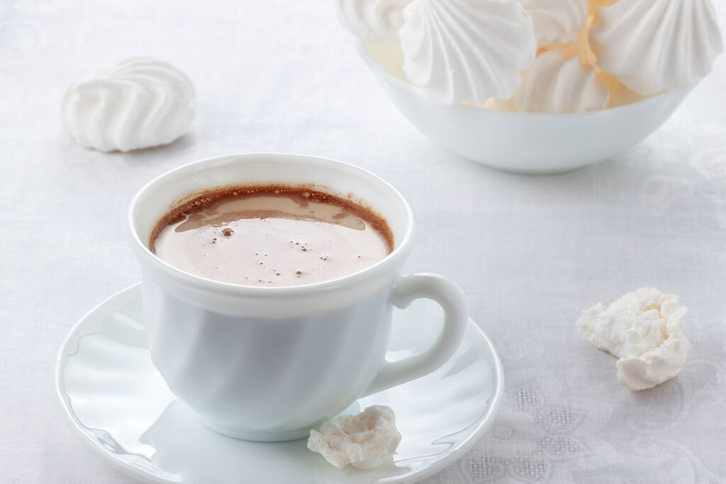 Na mesa está uma xícara de café fresco com creme e um bis suave e arejado
 - Foto, Imagem