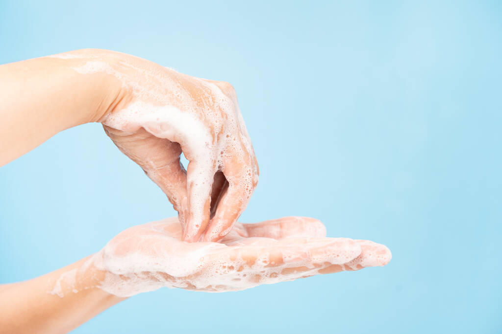 Закрыть азиатских женщин, очищающих руки с белыми мыльными пузырями на синем фоне. Демонстрация мытья рук для защиты от вирусов. Концепции гигиены и профилактики ковида 19
 - Фото, изображение