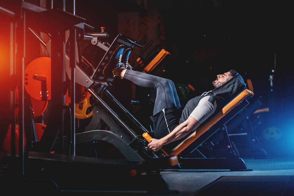 молодой человек имеет ноги тренировки в современном тренажерном зале
 - Фото, изображение