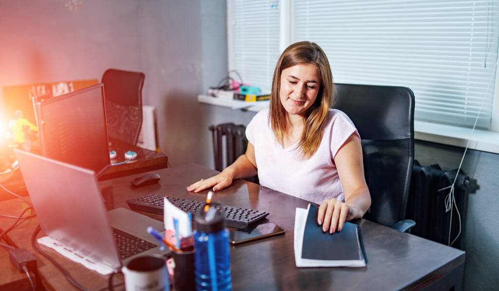 Eine geschäftige Büroangestellte sitzt am Schreibtisch und benutzt einen Laptop. Geschäftskonzept. - Foto, Bild