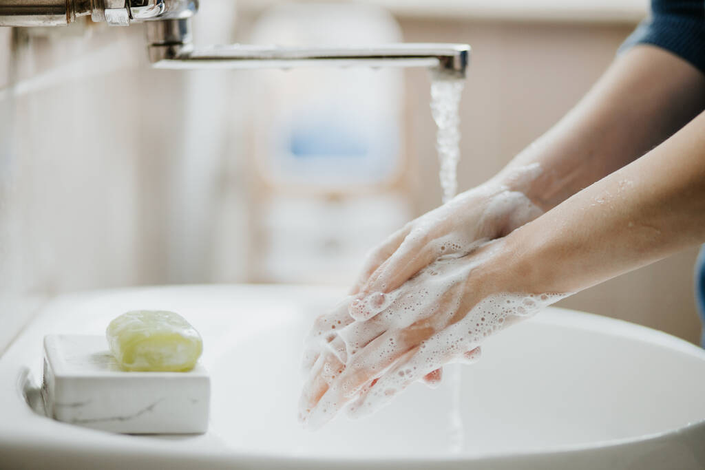 Gros plan d'une femme se lavant les mains dans la salle de bain pour prévenir une infection virale à Covid-19. Lavage recommandé avec du savon et de l'eau courante pendant la pandémie de coronavirus
. - Photo, image