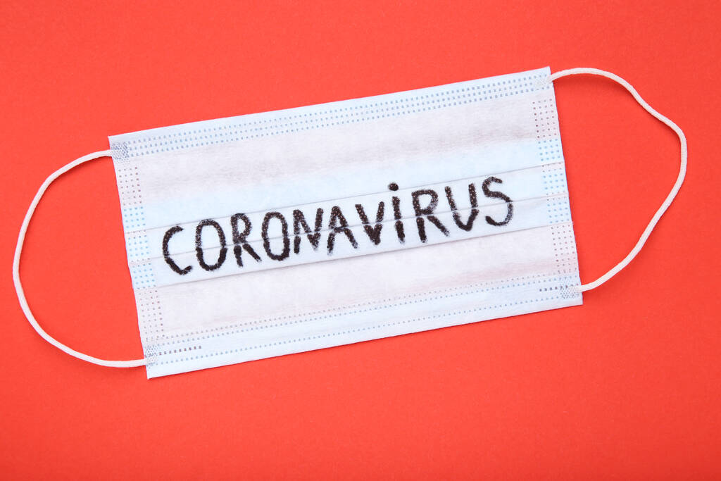 Kırmızı arkaplanda Coronavirus metni olan maske - Fotoğraf, Görsel