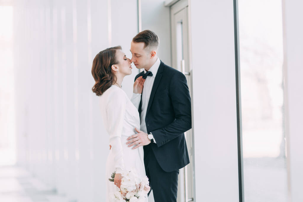 The bride and groom's romantic photo shoot. The newlyweds are happy together. Stylish modern couple in a light interior.  - Photo, Image