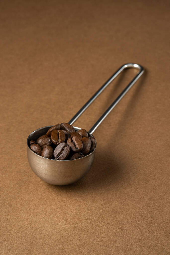Colher de medição cheia de café em uma superfície marrom. Close-up
. - Foto, Imagem