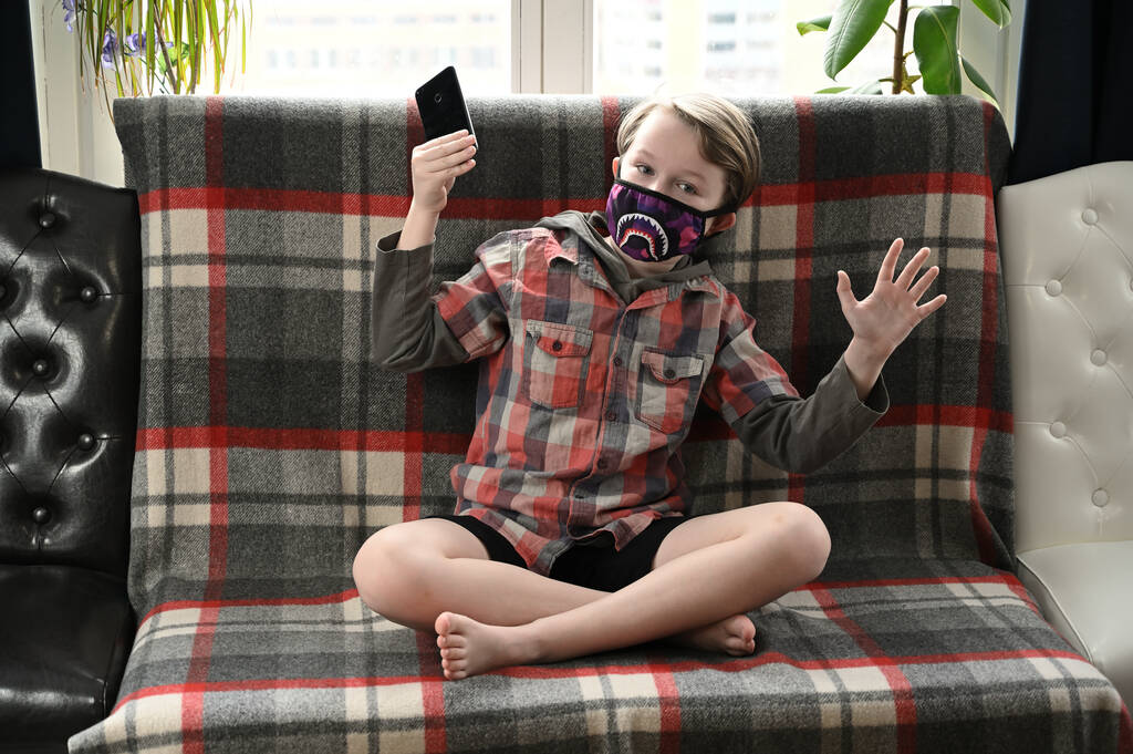 写真の男の子子供で医療面白いマスクで隔離室内で自宅でプレイ上のスマートフォン - 写真・画像
