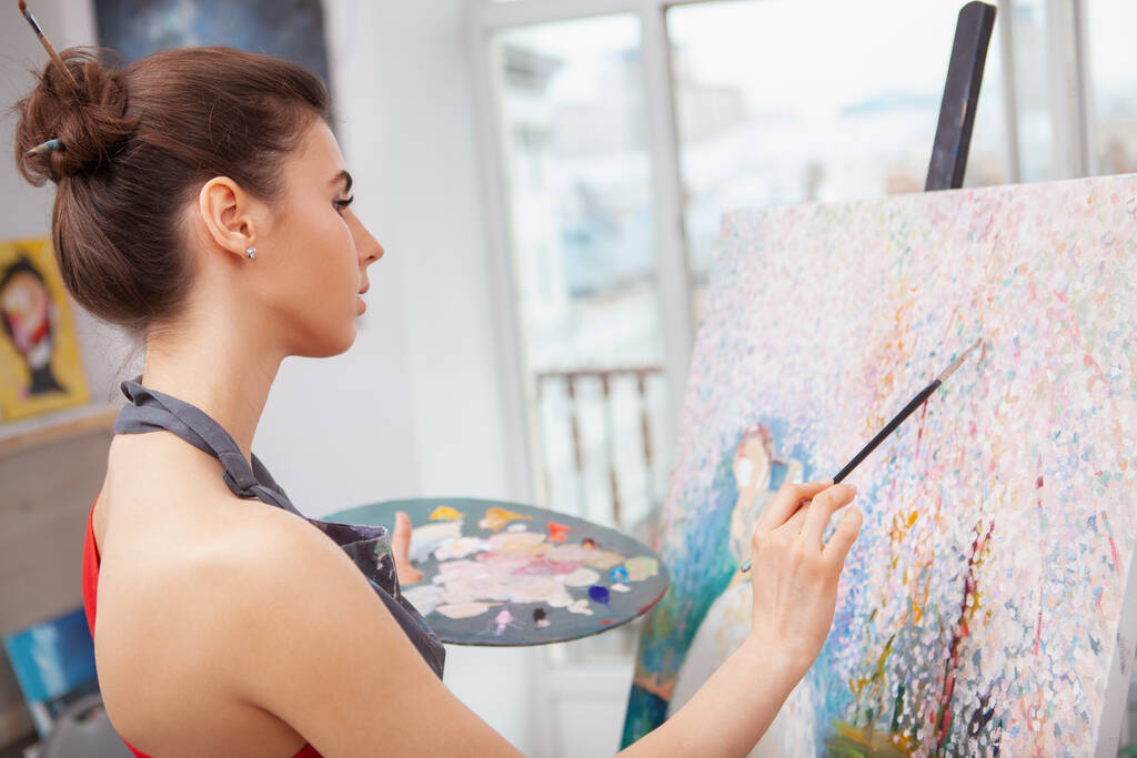 Nahaufnahme einer schönen jungen Frau, die sich beim Malen eines Bildes im Kunstunterricht entspannt - Foto, Bild