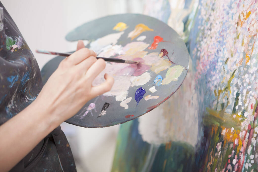 Gros plan d'une artiste féminine mélangeant de la peinture à l'huile sur une palette
 - Photo, image