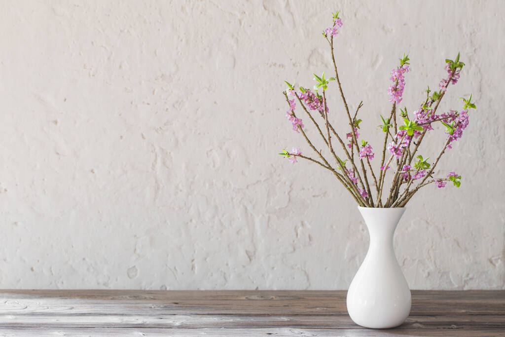 daphne bloemen in vaas op oude houten tafel op achtergrond wit w - Foto, afbeelding