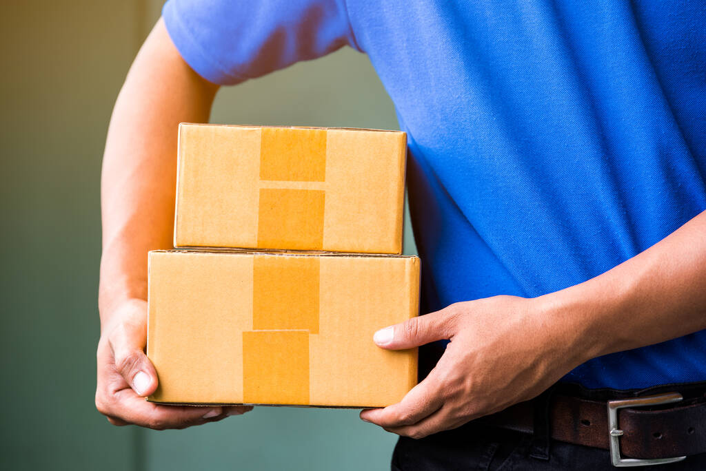 Close up Delivery man in blue uniforms holding parcel cardboard box. - Photo, Image