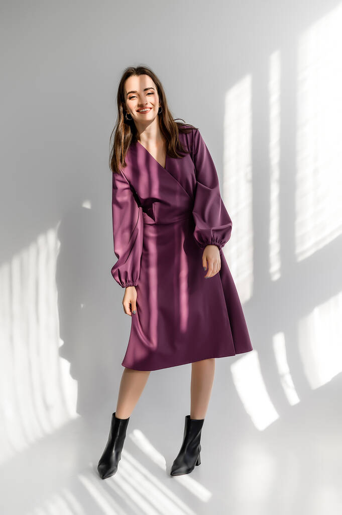 Привлекательная темноволосая женщина в фиолетовом клетчатом платье на белом фоне. Фотосессия для каталога одежды
 - Фото, изображение