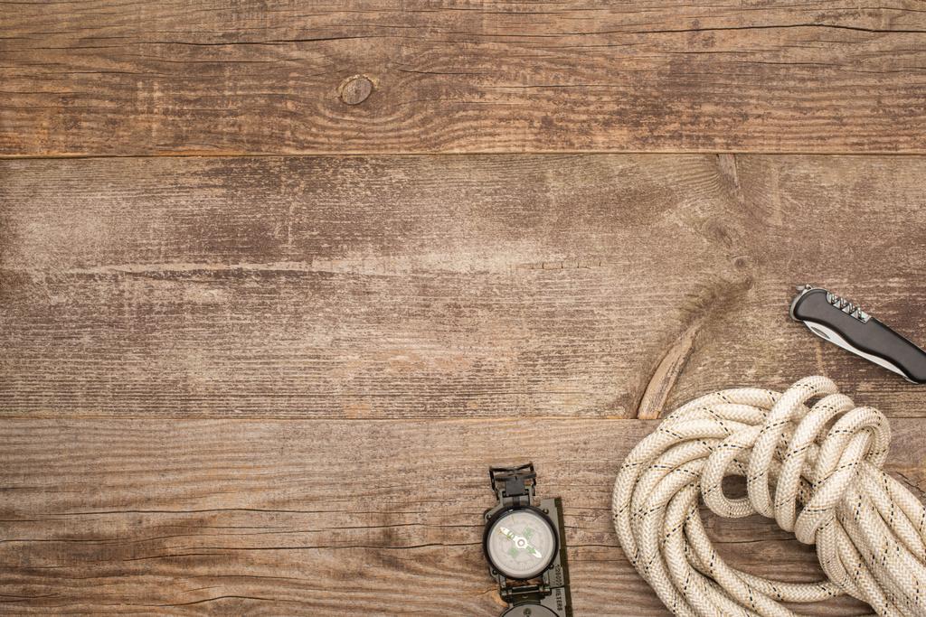 pohled shora na kompas, turistické lano a jackknife na dřevěném povrchu - Fotografie, Obrázek