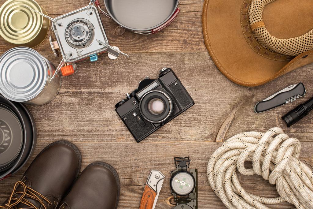 von oben mit Fotokamera, Hut, Stiefeln und Wanderausrüstung auf Holztisch - Foto, Bild
