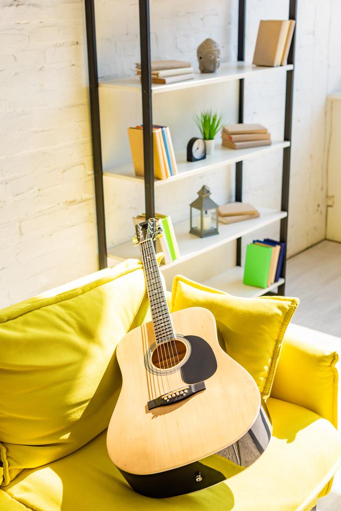 акустическая гитара на желтом диване в солнечном свете
 - Фото, изображение
