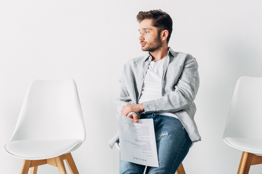 Jóképű férfi kezében önéletrajz, miközben ül széken az irodában - Fotó, kép