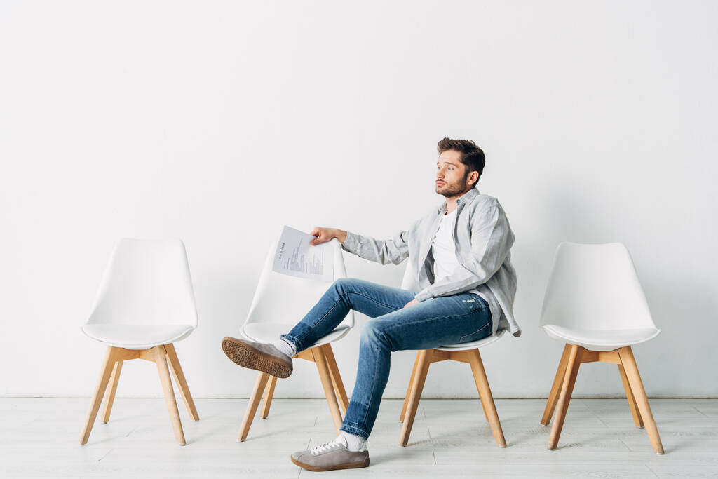 Вид сбоку человека с резюме, сидящего на стуле в офисе
 - Фото, изображение