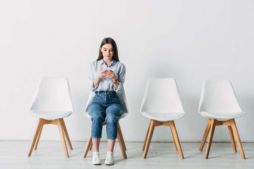 Young woman using smartphone while waiting for job interview in office  - Photo, Image